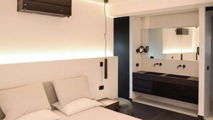 Un dormitorio moderno con una cama grande, armario empotrado y baño con lavamanos doble y espejo.