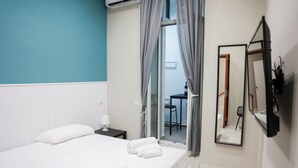 A hotel room with a bed, a nightstand, a mirror, and a sliding glass door leading to a balcony.