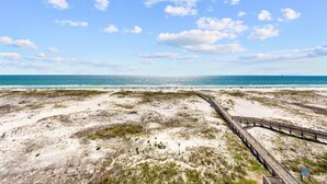 Ein Strand mit einer Holzpromenade, die zum Meer führt.