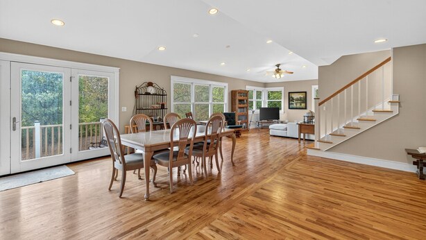 A spacious dining area with a wooden table and chairs, a staircase, and large windows with a view of greenery. - Secluded Woodland Retreat Near Starved Rock Park 4 Bedroom Home (Ottawa)