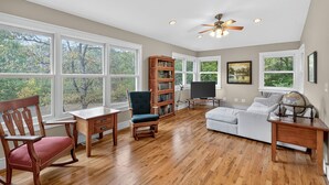 A spacious living room with hardwood flooring, a rocking chair, a bookshelf, a television, and a globe on a side table. - Secluded Woodland Retreat Near Starved Rock Park 4 Bedroom Home (Ottawa)