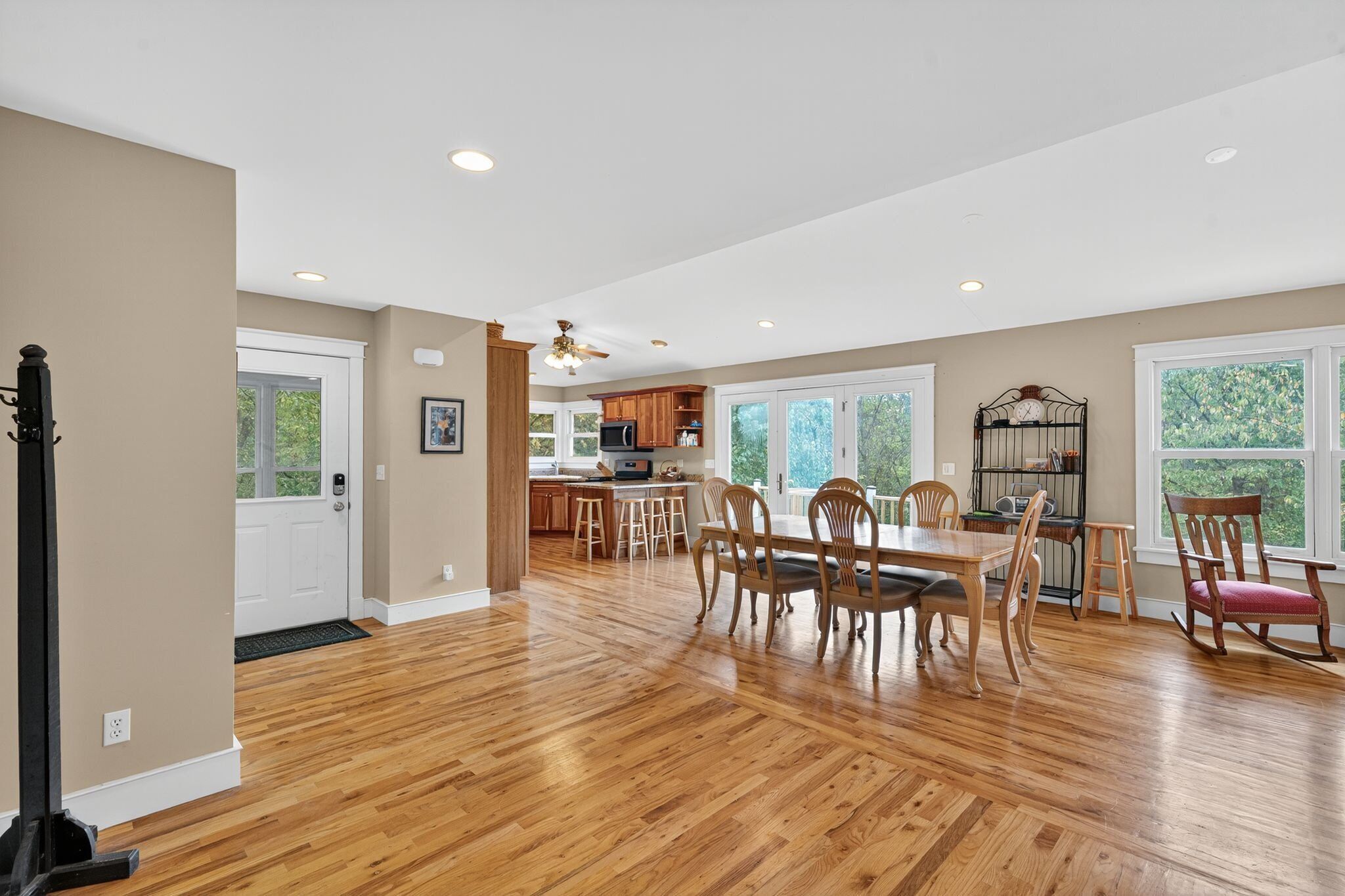 A spacious kitchen with wooden cabinets, a dining area with a table and chairs, and a view of greenery outside.