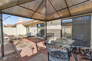 An outdoor patio with a covered seating area, a grill, and a sliding glass door leading to a covered garage. - Chilled Tempe Oasis Shaded BBQ Lounge Near ASU 2 Bedroom Home (Tempe)