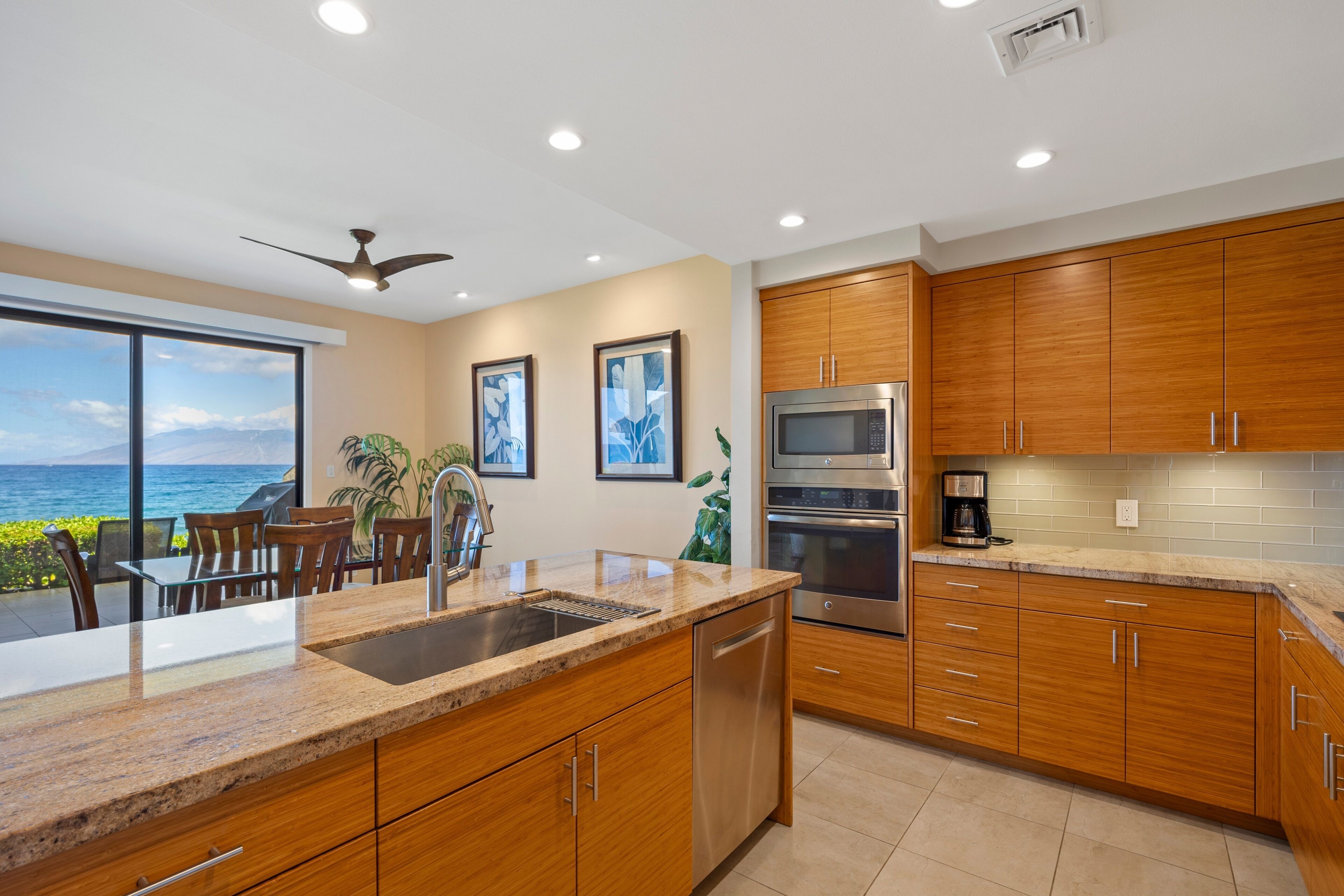 A modern kitchen with wooden cabinets, stainless steel appliances, and a view of the ocean.