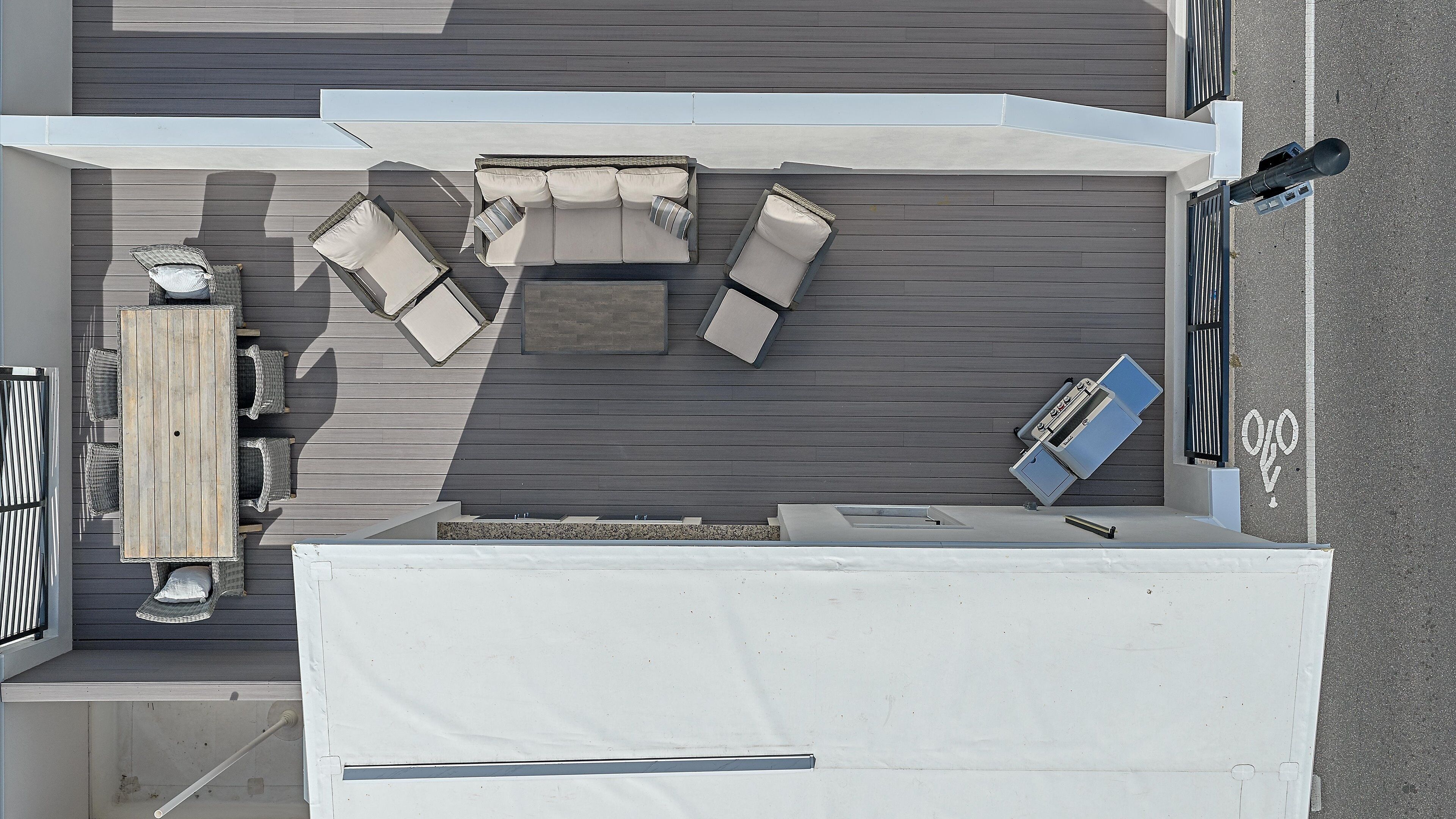 Eine Terrasse im Freien mit Holzdeck, einem weißen Tisch und mehreren Liegestühlen.