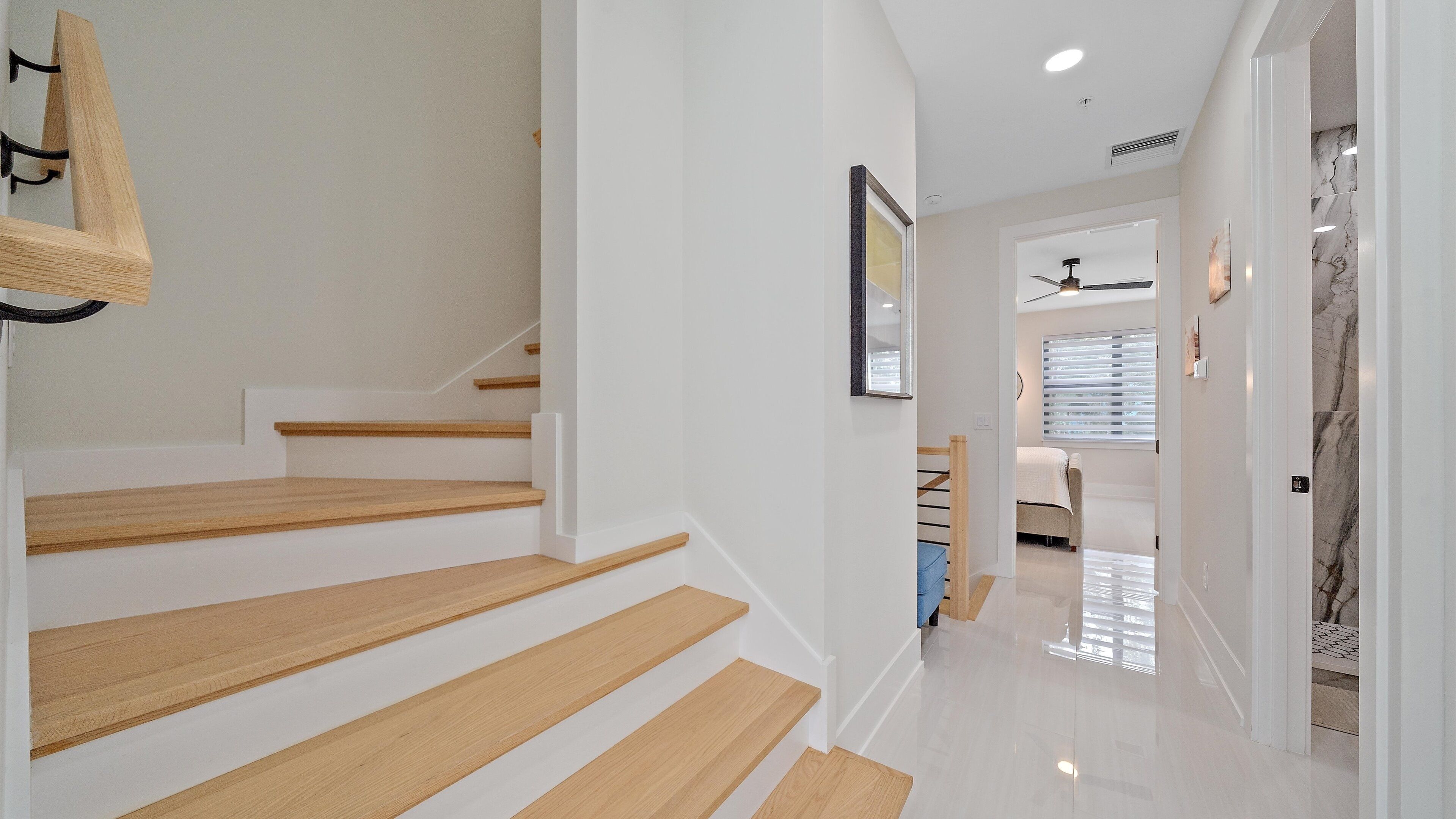 A modern staircase with wooden steps and a wall-mounted light fixture.