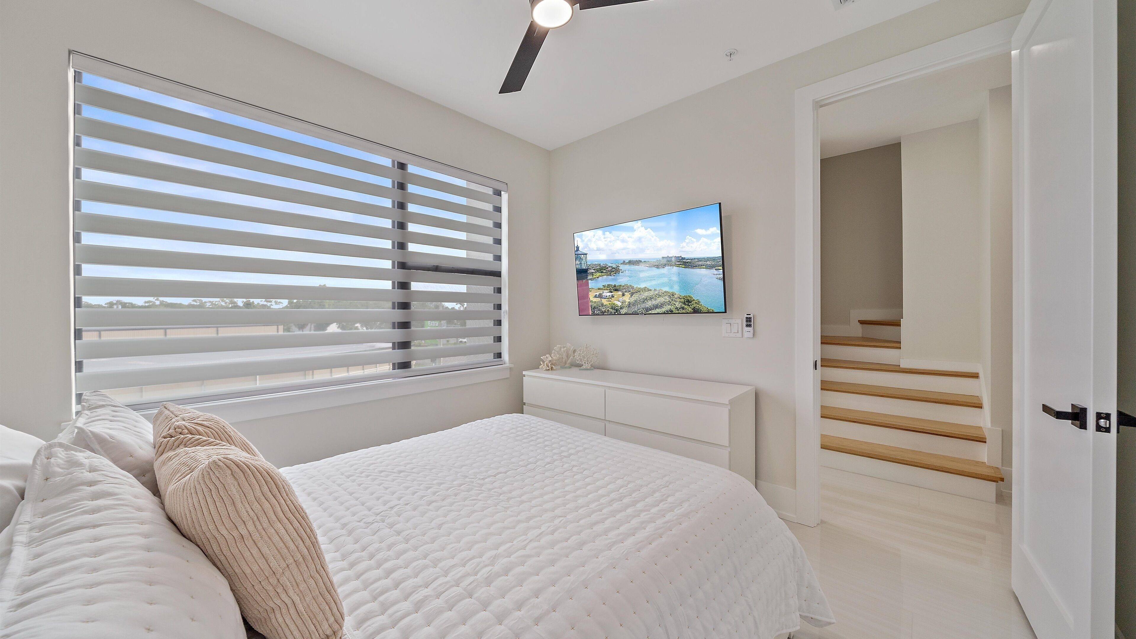 Una camera da letto con un letto, una TV a parete e vista sull'esterno attraverso la finestra.