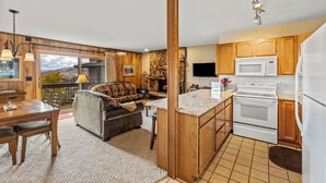 A modern kitchen with wooden cabinets, a built-in microwave, and a double oven. - Storm Meadows I -1-Bedroom + Studio (Retractable Privacy Wall), 2-Bath (Steamboat Springs)