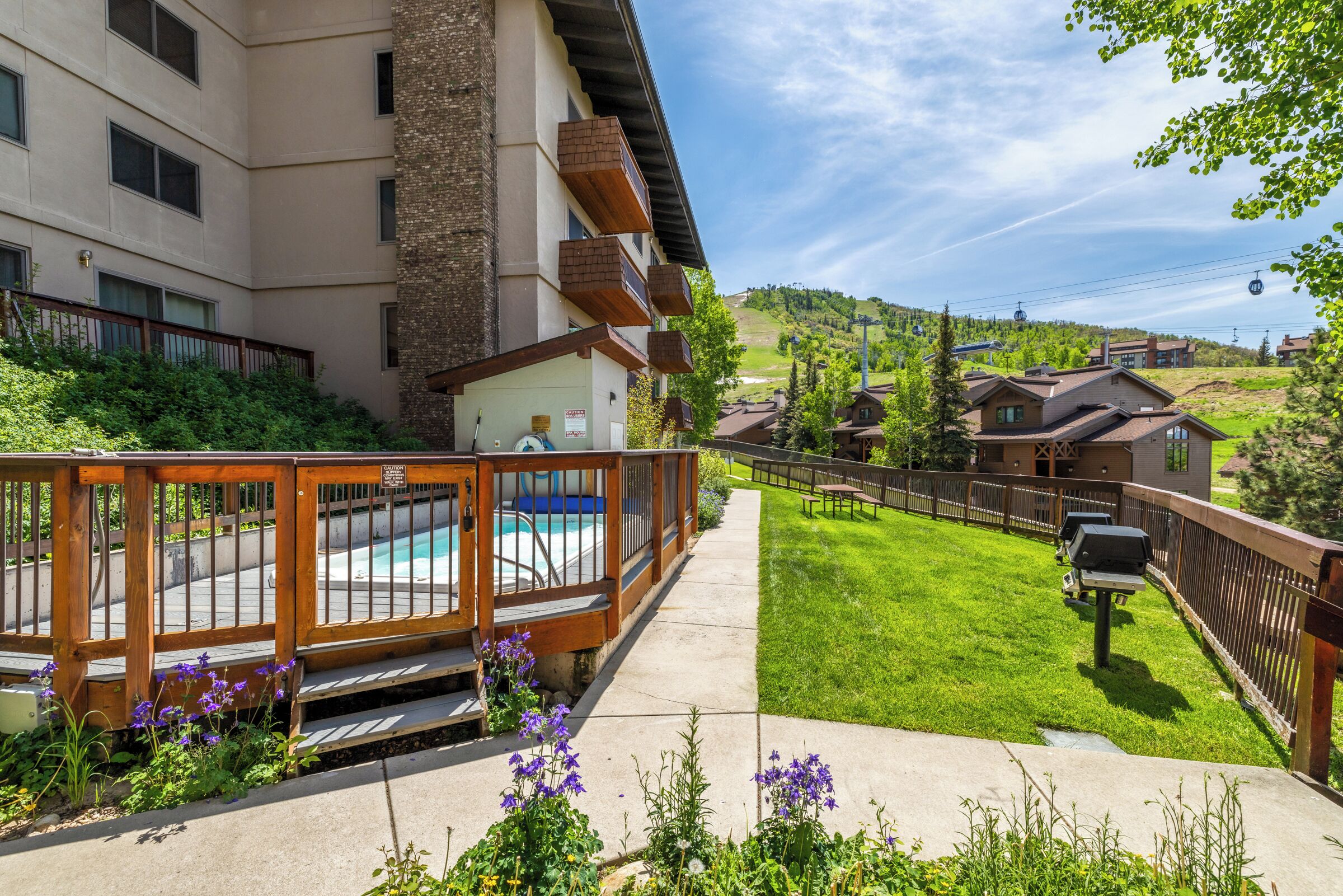 A residential building with a swimming pool, a barbecue area, and a well-maintained lawn.