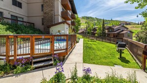 A residential building with a swimming pool, a barbecue area, and a well-maintained lawn. - Storm Meadows I -1-Bedroom + Studio (Retractable Privacy Wall), 2-Bath (Steamboat Springs)