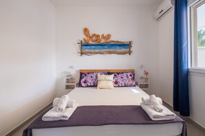 Hotelkamer met een bed, een 'Love'-bord, bloemenkussens en handdoeken.