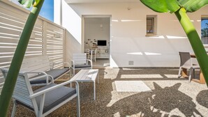 Eine Terrasse mit Gartenmöbeln, einem Fernseher und einer Tür zu einem Innenraum.