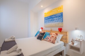 Ett hotellrum med en säng, handdukar, en tavla och ett nattduksbord.