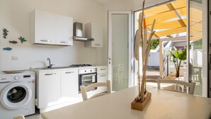Eine moderne Küche mit Waschmaschine, einem Esstisch und Stühlen sowie Blick ins Freie.