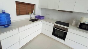A modern kitchen with white cabinets, a stainless steel sink, a built-in oven, and a microwave. - Great Sea view Mountain Villa (Koh Samui)