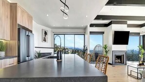 Una cocina moderna con una isla grande, un refrigerador empotrado y una chimenea.