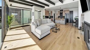 Una sala de estar moderna con un amplio sofá modular, una mesa de centro y una cocina visible al fondo.