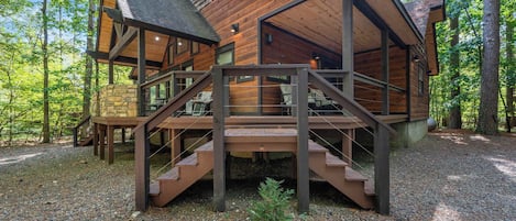 Een chalet met een houten gevel, een stenen fundering en een houten terras met een trap naar de ingang.