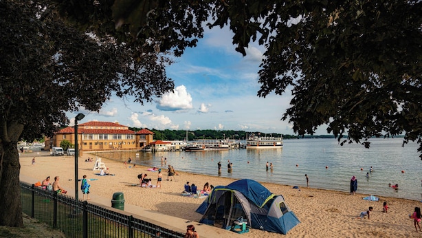 A beach with a tent, a building with a red roof, and a body of water.