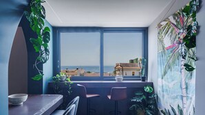 A balcony with a view of the sea, a table with chairs, and potted plants. - Tropicalia Suites by Wonderful Italy  (Aci Castello)