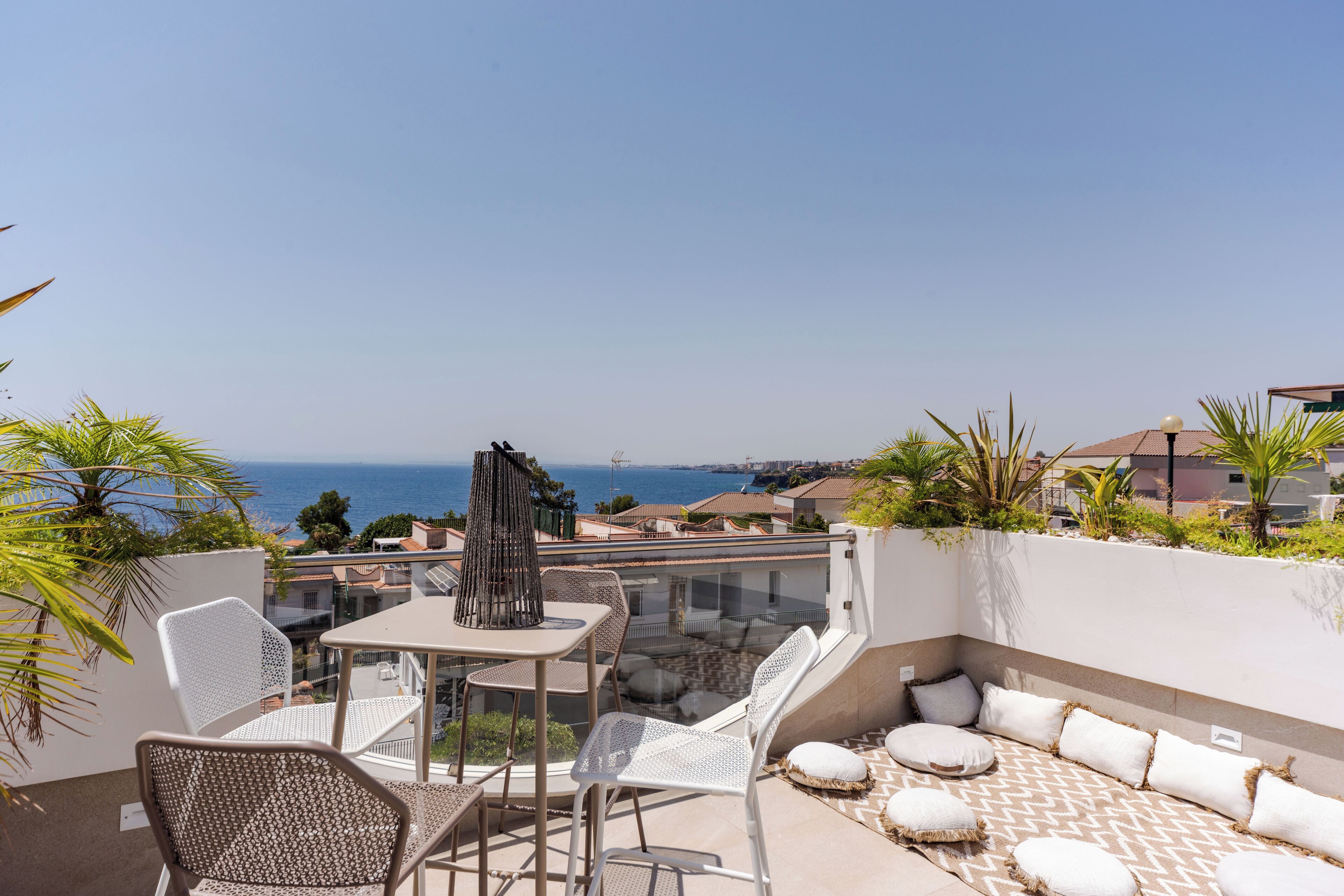 Un espace extérieur aménagé avec une table et des chaises, un canapé à motifs et une vue sur la mer.