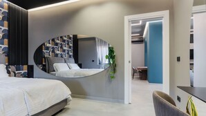 A modern bedroom with a curved mirror, a bed, a desk, and a chair. - Tropicalia Suites by Wonderful Italy  (Aci Castello)