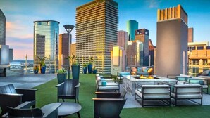 A rooftop terrace with outdoor seating, surrounded by high-rise buildings.