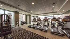 A gym with treadmills, weight machines, and dumbbells.