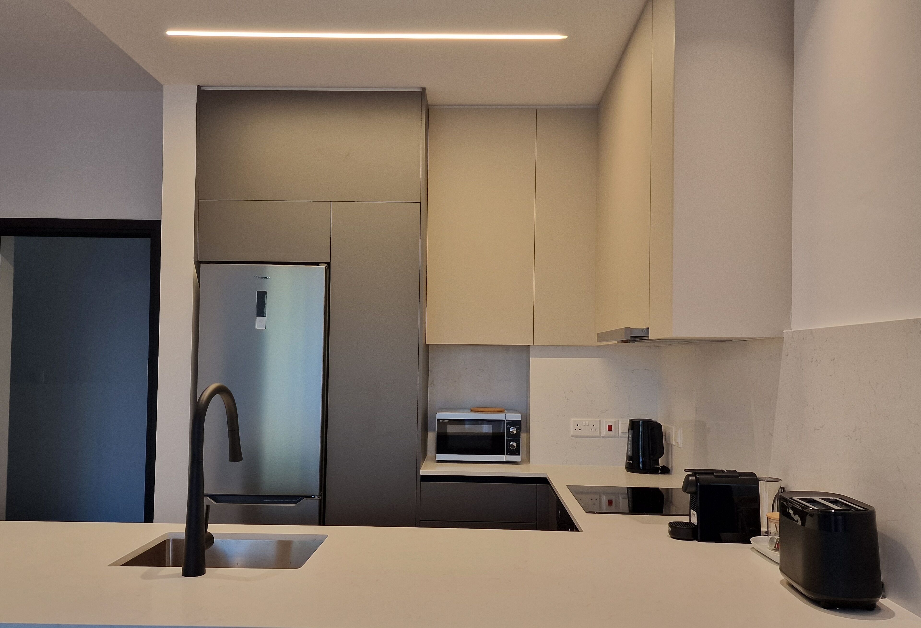 Una cocina moderna con un refrigerador de acero inoxidable, un microondas, una cafetera y un tostador.