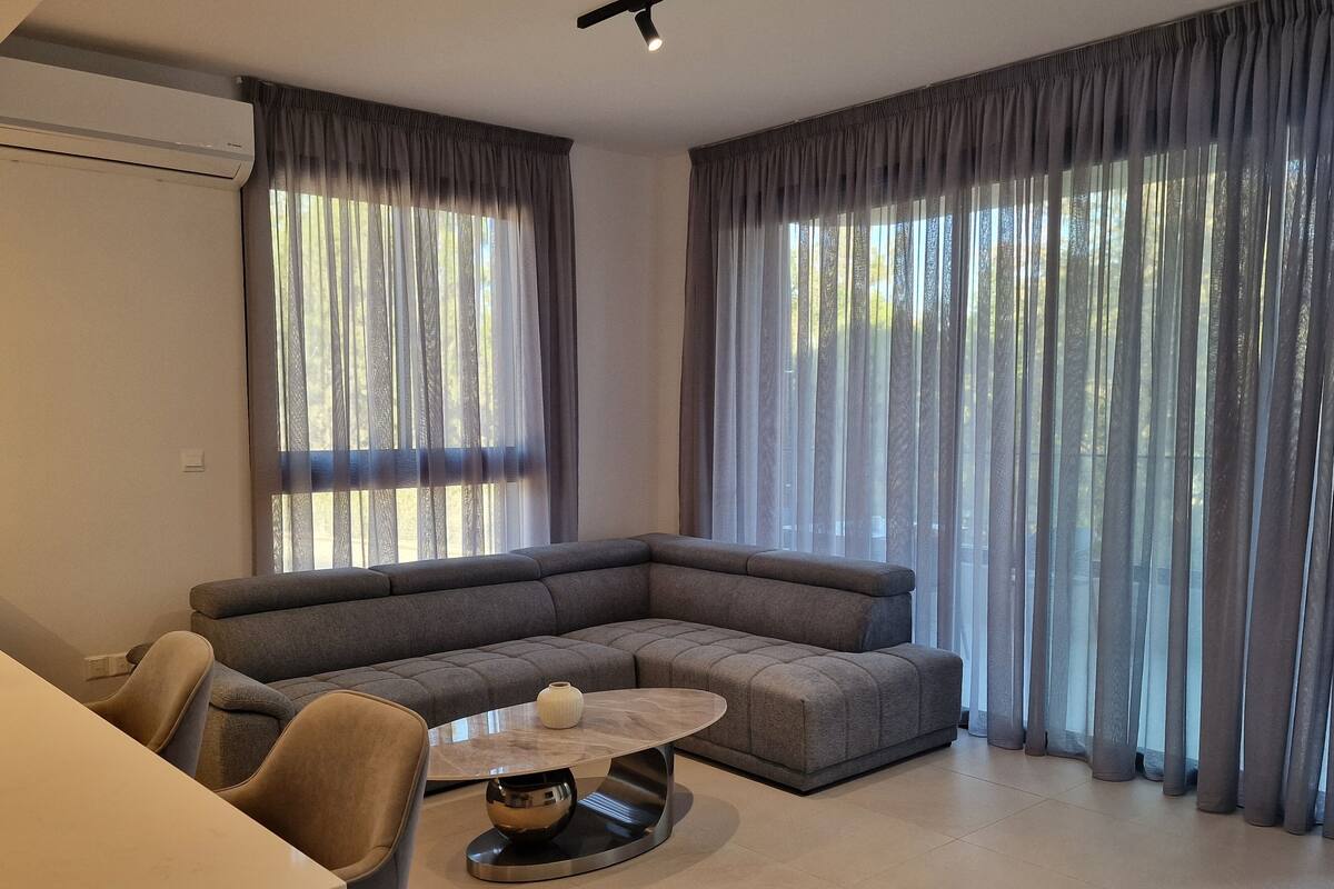 A modern living room with a sectional sofa, a round coffee table, and a dining area with chairs.