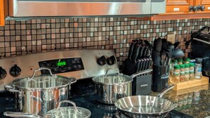A kitchen with stainless steel cookware, a digital clock, and a spice rack. - The Pines at New Albany | Sleeps 8 | Acre Lot (New Albany)