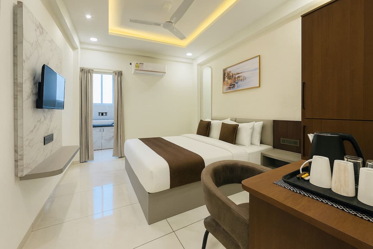Une chambre d’hôtel avec un lit, un bureau avec des tasses, une télévision et un tableau au mur.