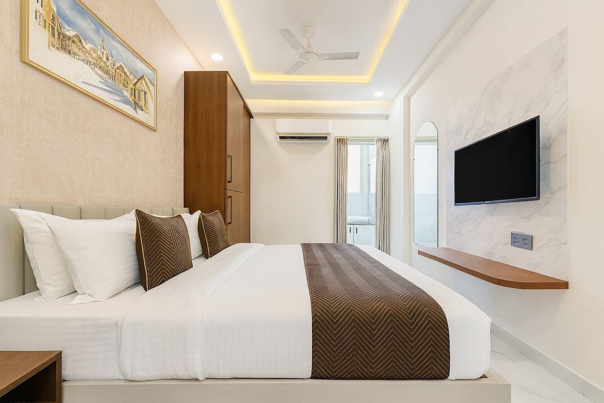 Une chambre d’hôtel moderne avec un grand lit, un téléviseur fixé au mur et un ventilateur de plafond.