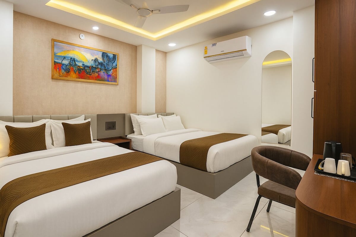 Une chambre d’hôtel avec deux lits, un bureau, une chaise, un tableau au mur et un appareil de climatisation.