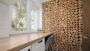 Een keuken met een houten wand, een raam met uitzicht op bomen en een zwart-wit geruite vloer.