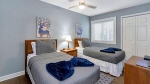 Ein Schlafzimmer mit zwei Betten, einem Deckenventilator und Bildern an den Wänden.