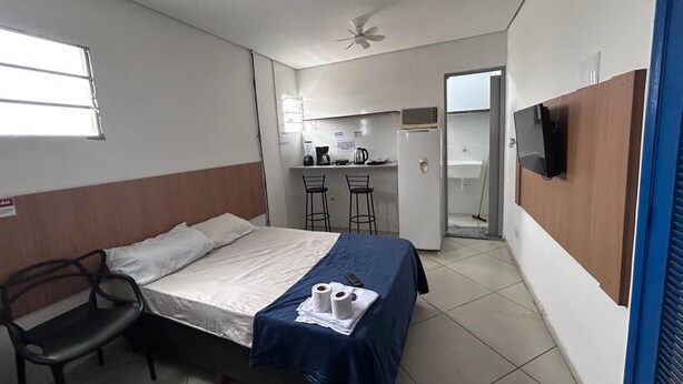 A compact hotel room with a single bed, a desk with two chairs, a microwave, and a television.