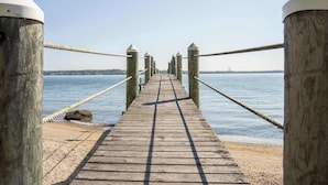 A wooden pier leading to a calm body of water with a clear sky. - Waterfront Saunderstown Estate with Private Dock (North Kingstown)