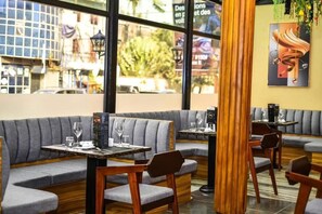 Un interior de restaurante con cabinas tapizadas en gris, mesas y sillas de madera.
