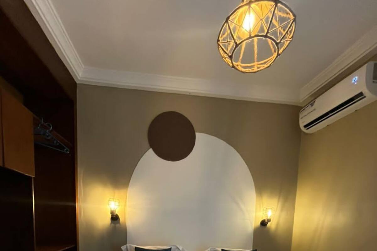 A hotel room with a large bed, two bedside lamps, a circular wall decoration, and a wardrobe.