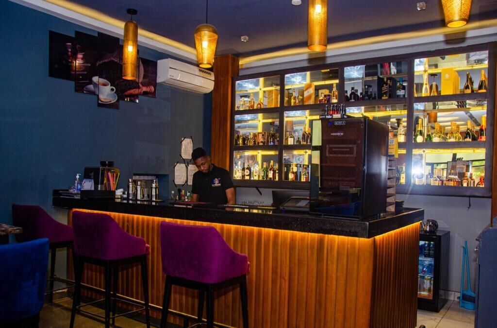 A bar area with a counter, purple bar stools, and a bartender.