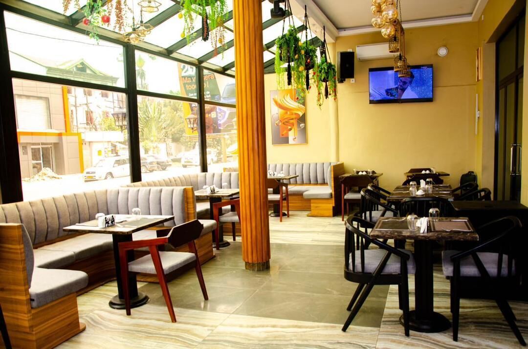Un restaurante con asientos tipo cabina, mesas y plantas colgantes.