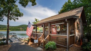 Een houten blokhut met een steiger, een Amerikaanse vlag en een bord waarop staat dat een visvergunning vereist is.