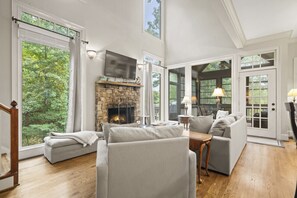 A spacious living room with a stone fireplace, large windows, and a cozy seating area. - Ridgeview Retreat in Big Canoe (Big Canoe)
