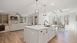 A spacious kitchen with a large island, white cabinetry, and pendant lighting. - Sycamore's Haven in Big Canoe with Hot tub (Big Canoe)