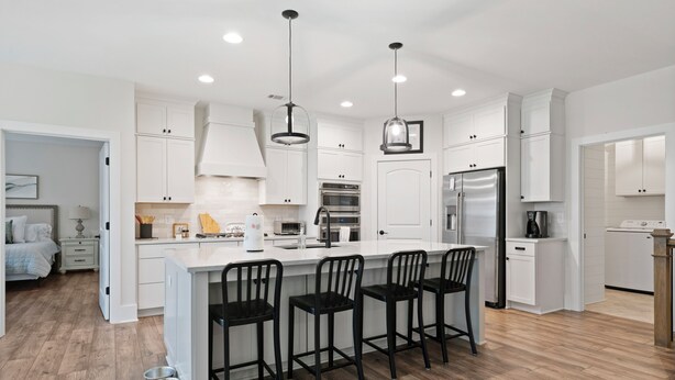 A modern kitchen with white cabinets, a central island with bar stools, stainless steel appliances, and pendant lighting. - Sycamore's Haven in Big Canoe with Hot tub (Big Canoe)