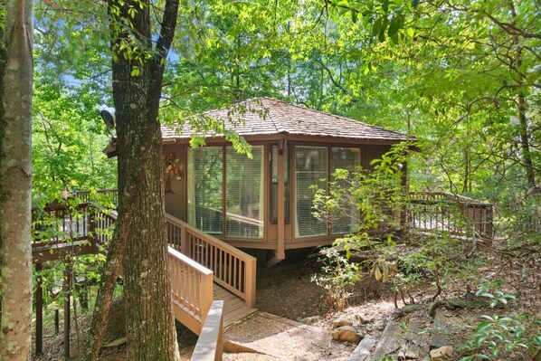 A wooden cabin with a covered deck, surrounded by dense forest. - Treetopper Knoll Chalet in Big Canoe (Jasper)