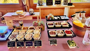 Une table de buffet proposant divers plats et accompagnements, une machine à café et un panneau indiquant qu’une récompense Google est offerte.