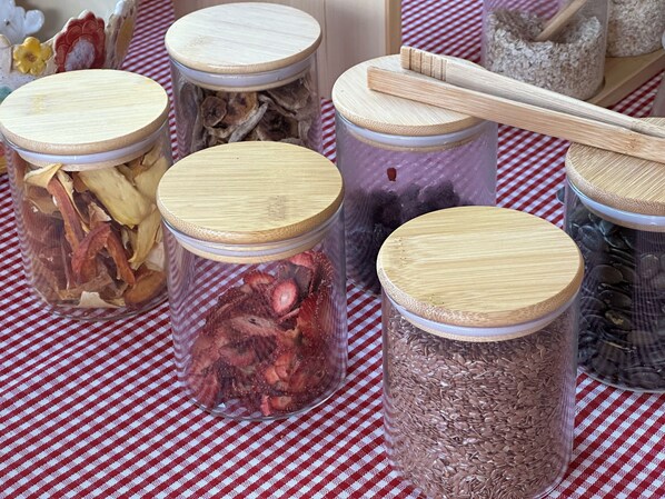 Several glass jars with wooden lids on a checkered tablecloth.