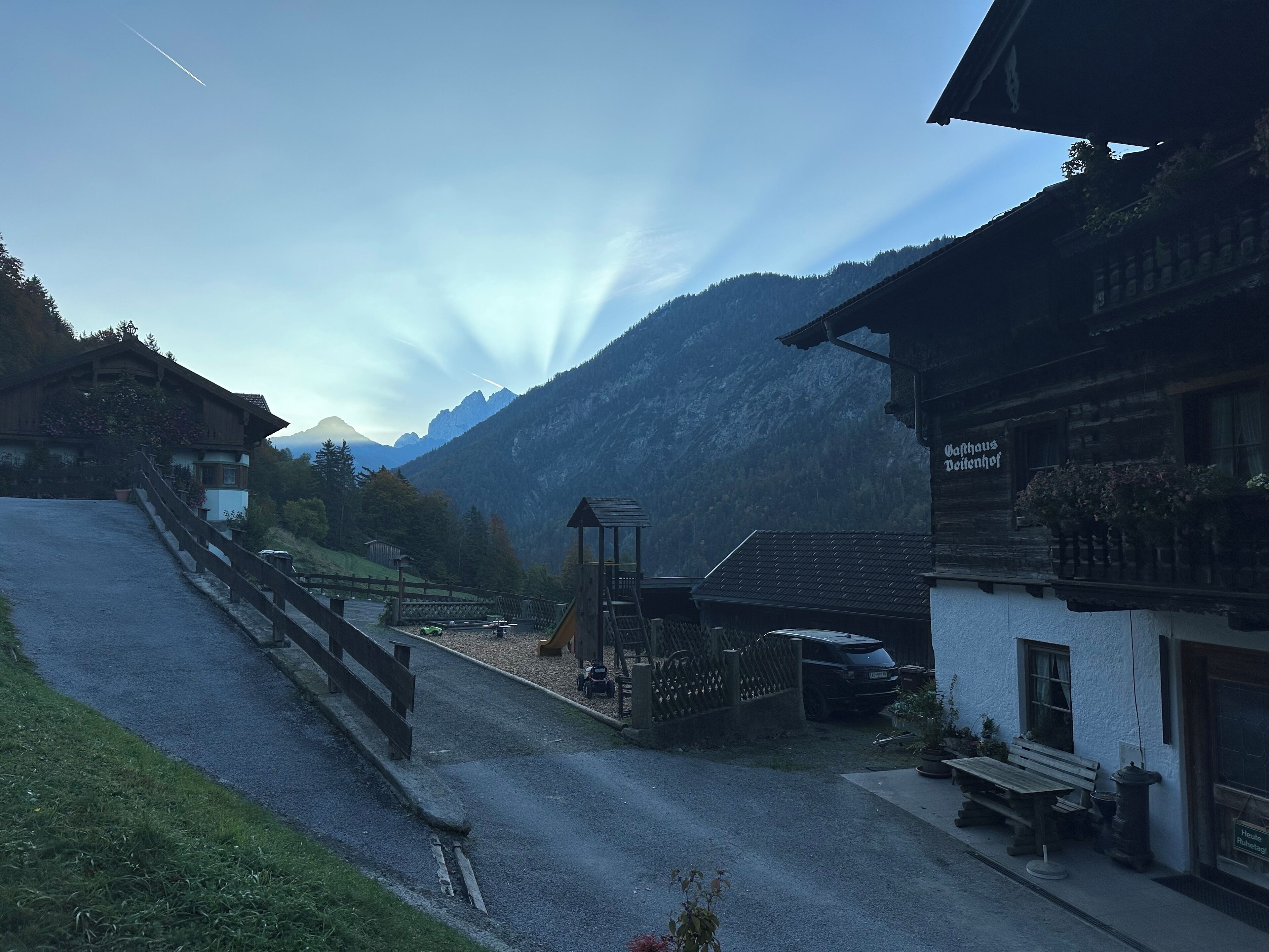 A mountain village with traditional wooden buildings, a paved road, and a bench outside a building.